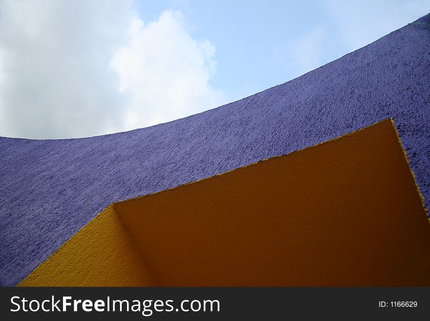 Curved purple and yellow building with sky in background