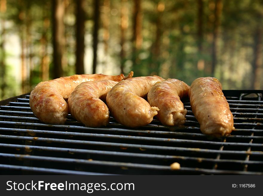 Few sausages put on a grill in forest. Few sausages put on a grill in forest