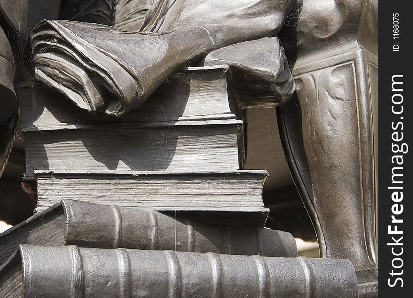 A detail of a statue including books and a newspaper. A detail of a statue including books and a newspaper.