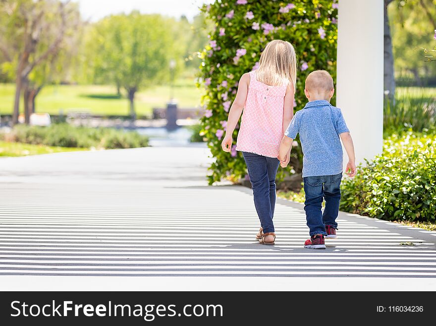 Little Brother and SIster Holding Hands And Walking At The Park