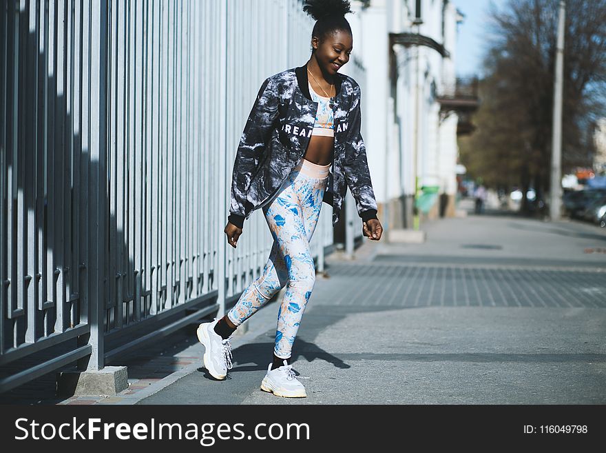 Woman Wearing Black Jacket And White Pants Standing On Grey Concrete Pavement