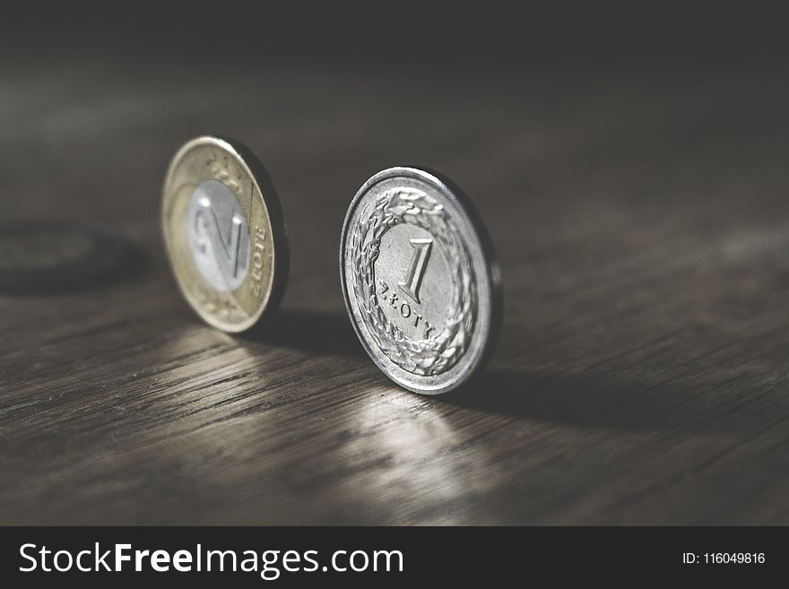 Photo Of Two Gold-colored And Silver-colored Coins Standing On Floor