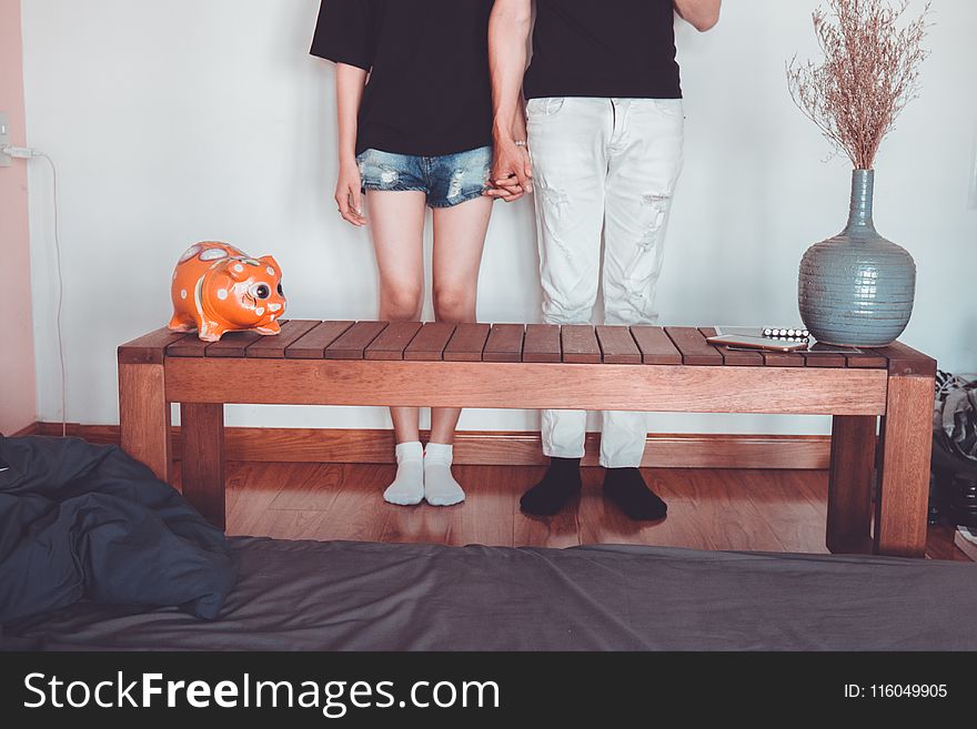 Woman and Man Holding Hand Standing Near Brown Coffee Table Inside Room