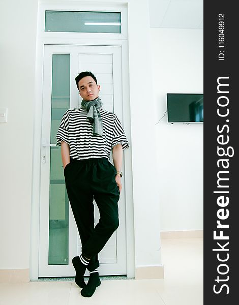 Man in Black and White Striped Shirt Leaning on Door