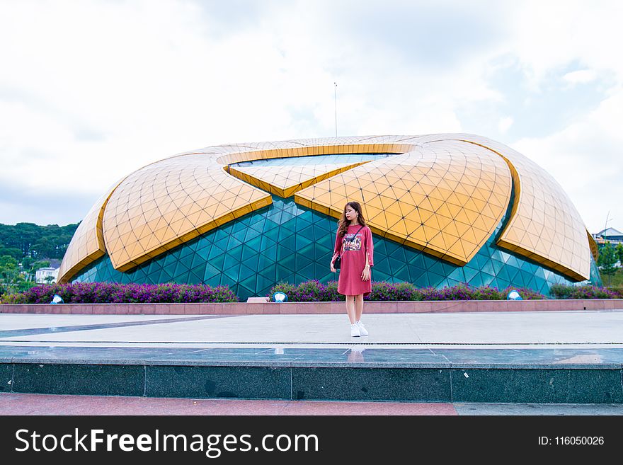 Woman Standing Near Blue and Yellow Dome Under White Cloudy Skies at Daytime