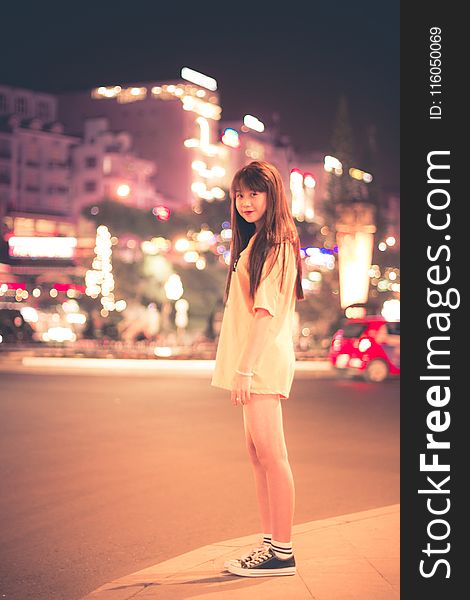 Woman in White Shirt Standing on Roadside during Night Time