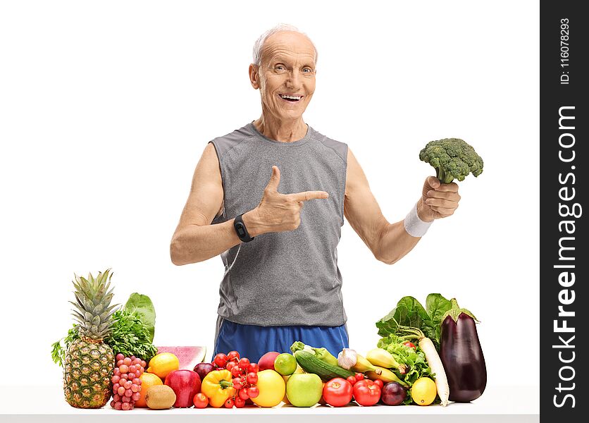 Elderly Man Behind A Table With Fruit And Vegetables Holding Bro