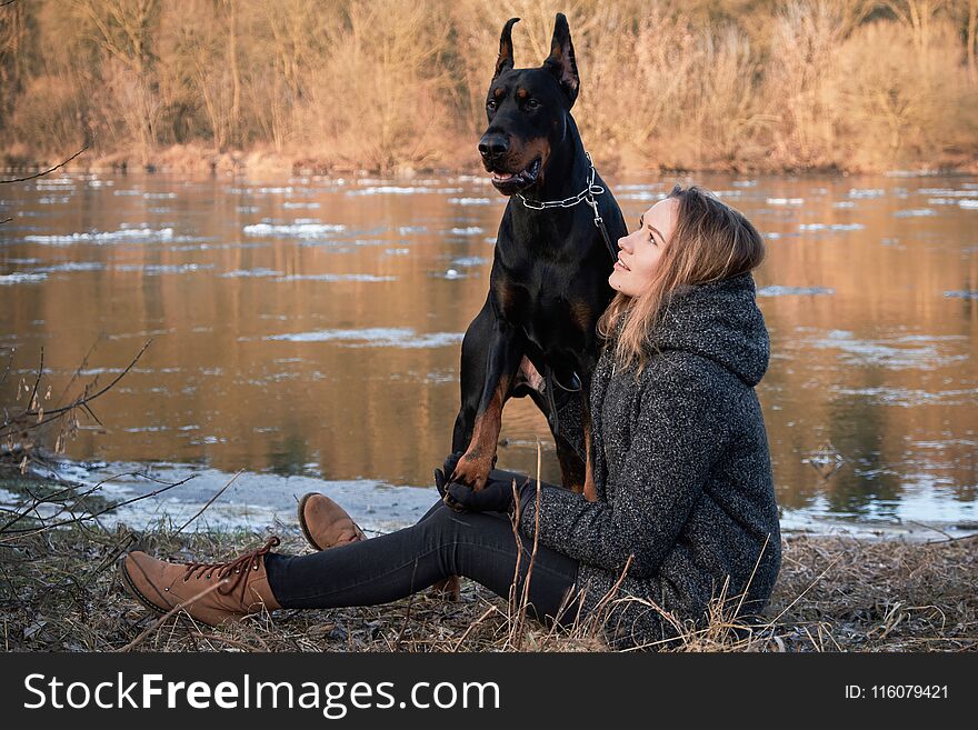 Portrait of beautiful young woman with her doberman dog. Warm natural color.