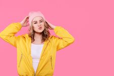 Crazy Beautiful Trendy Girl In Bright Yellow Jacket And Pink Beanie Hat Puckering Lips. Cool Young Woman Fashion Portrait. Stock Image Crazy Beautiful Trendy Girl In Bright Yellow Jacket And Pink Beanie Hat Puckering Lips. Cool Young Woman Fashion Portrait. Stock Image