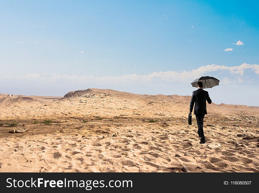 Businessman in suit with umbrella running in desert. Mixed media. Businessman in suit with umbrella running in desert. Mixed media