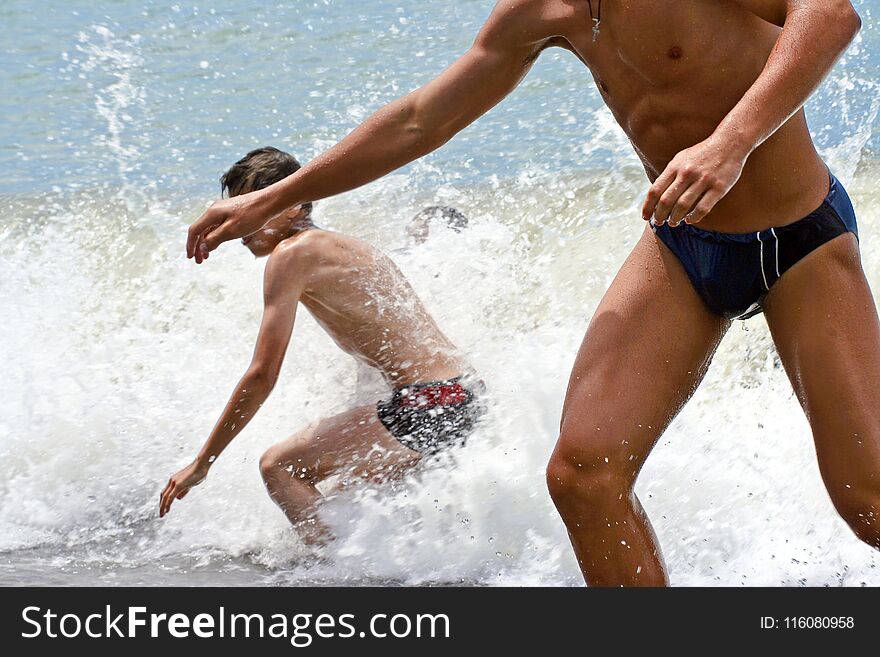 Two young people run out of the sea on the coast getting joy and mood in Sunny summer weather.