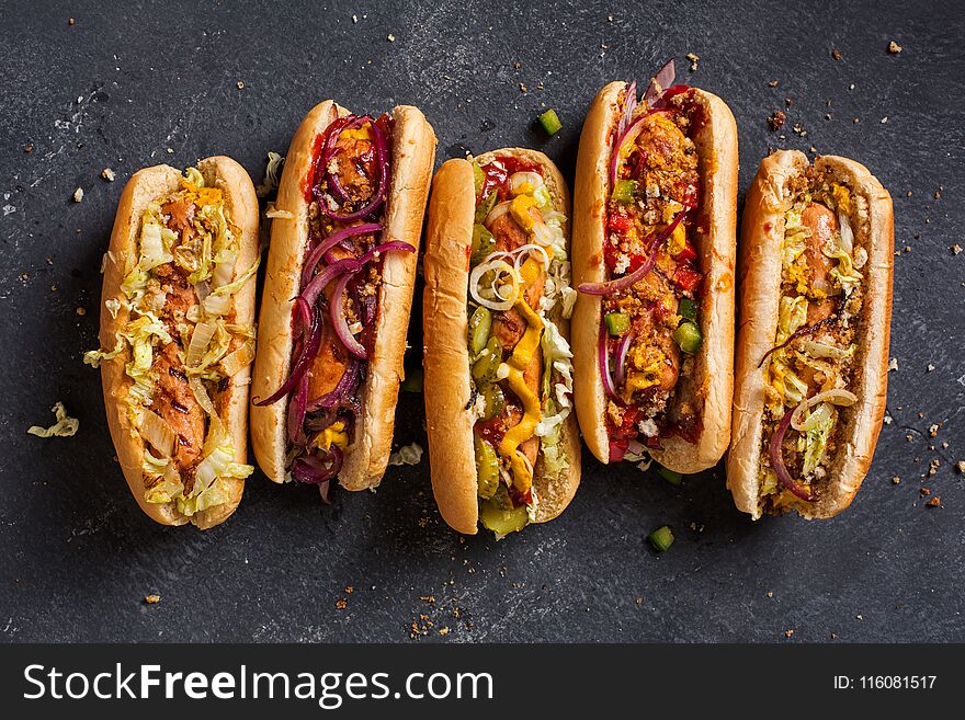 Hot dogs with a sausage on a fresh rolls garnished with mustard and ketchup and served with different toppings. Hot dogs with a sausage on a fresh rolls garnished with mustard and ketchup and served with different toppings.