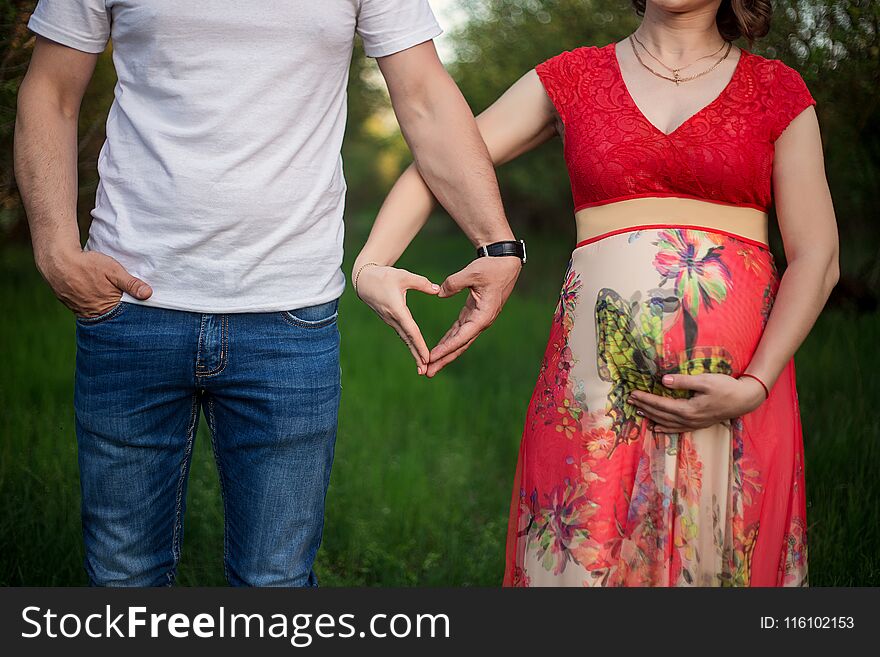 A happy pregnant couple made from hands made of a heart