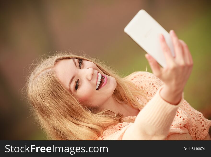 Cheerful blonde girl taking selfie.