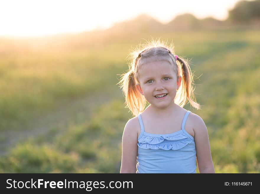 The girl is three years old, child on the field at sunset