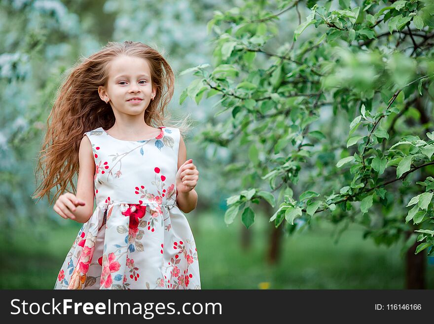 Adorable Little Girl In Blooming Apple Tree Garden On Spring Day