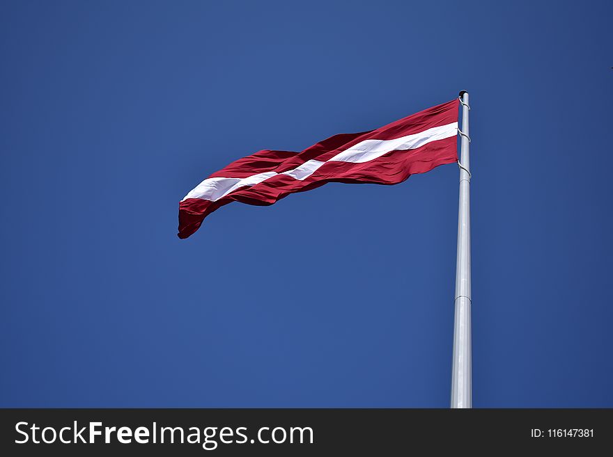 Red and White State Flag Waving Under Blue Sky at Daytime