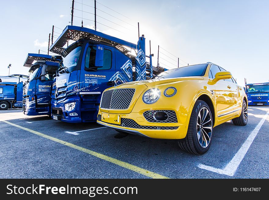 Yellow Vehicle Parked Beside Blue Truck