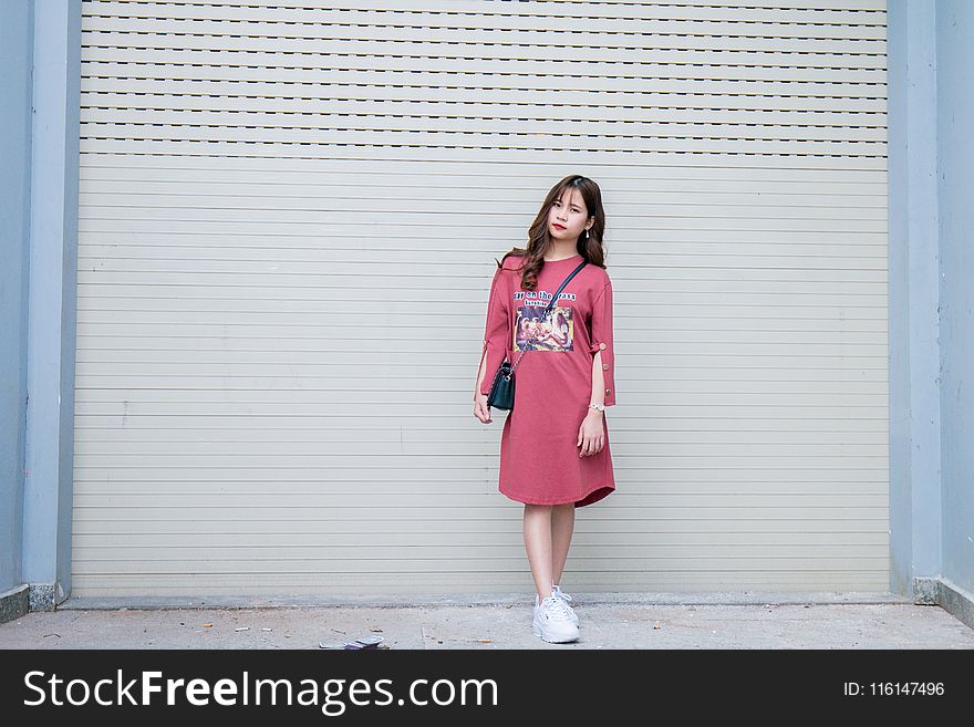Woman Wearing Pink Long-sleeved Dress Standing Behind the Wall