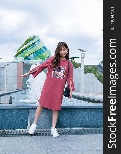 Woman Standing Beside Gray Concrete Outdoor Fountain Under Blue And White Cloudy Skies At Daytime