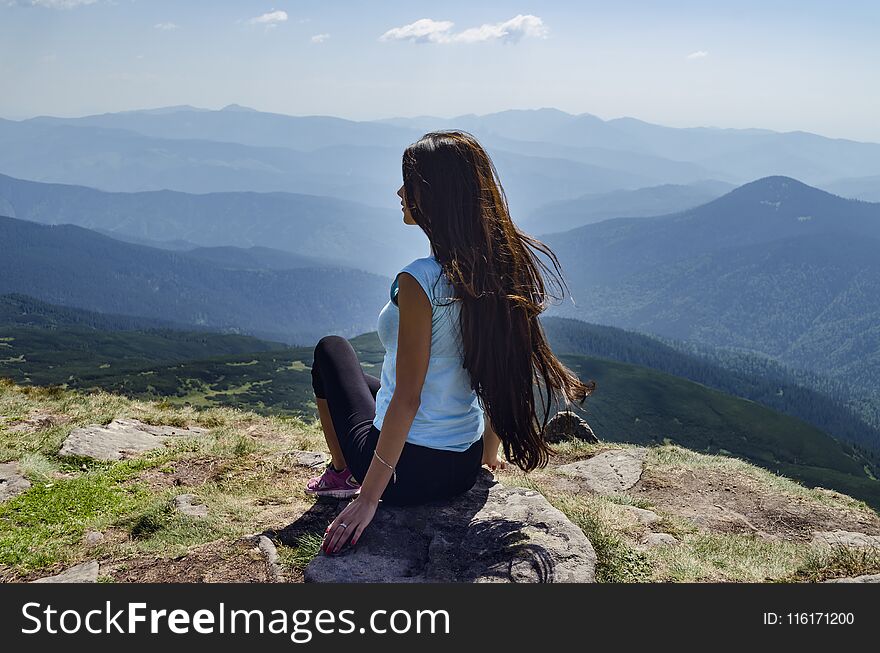 Girl with long hair on top of the mountain, on the background of the Carpathian Mountains, on a warm summer day. Girl with long hair on top of the mountain, on the background of the Carpathian Mountains, on a warm summer day