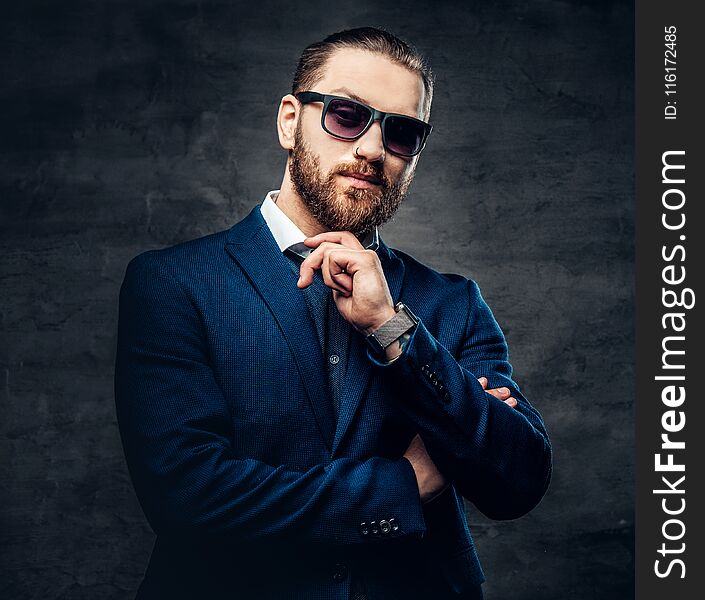 Studio portrait of bearded male in sunglasses and piercing in a nose.