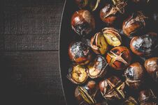 Close Up Of Roasted Chestnuts In Iron Grilling Pan Over Rustic Wooden Table, Top View, Copy Space Royalty Free Stock Images
