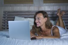 Young Stylish Attractive And Beautiful Caucasian Woman 30s Lying On Bed At Night In Home Bedroom Using Internet At Laptop Computer Stock Photo