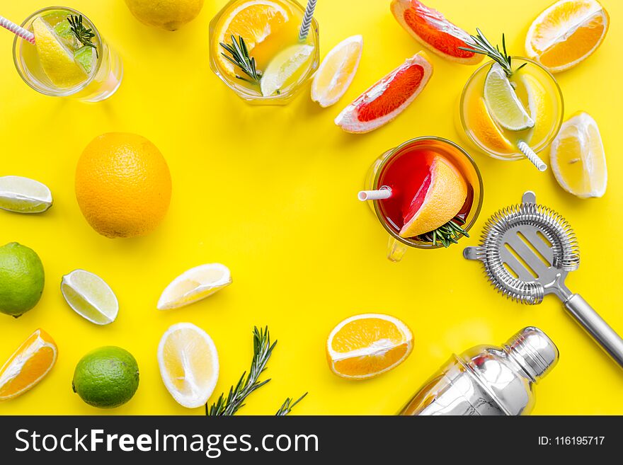 Mix exotic fruit cocktail with alcohol. Shaker and strainer near citrus fruits and glass with cocktail on yellow background top view.