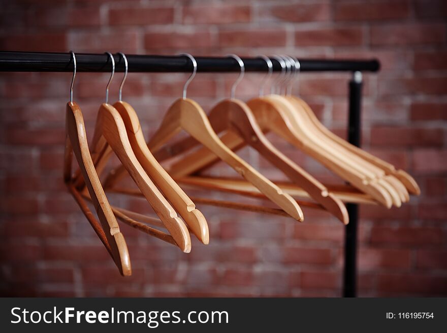 Clothes rail with hangers on blurred brick background