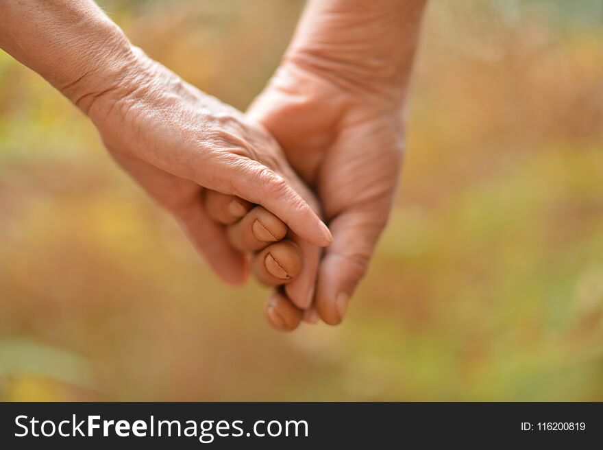 Elderly couple holding hands together