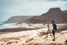 Photographer With Camera In Desert Admitting Unique Landscape Of Sand Dunes Volcanic Cliffs On The Atlantic Coast. Baia Royalty Free Stock Image