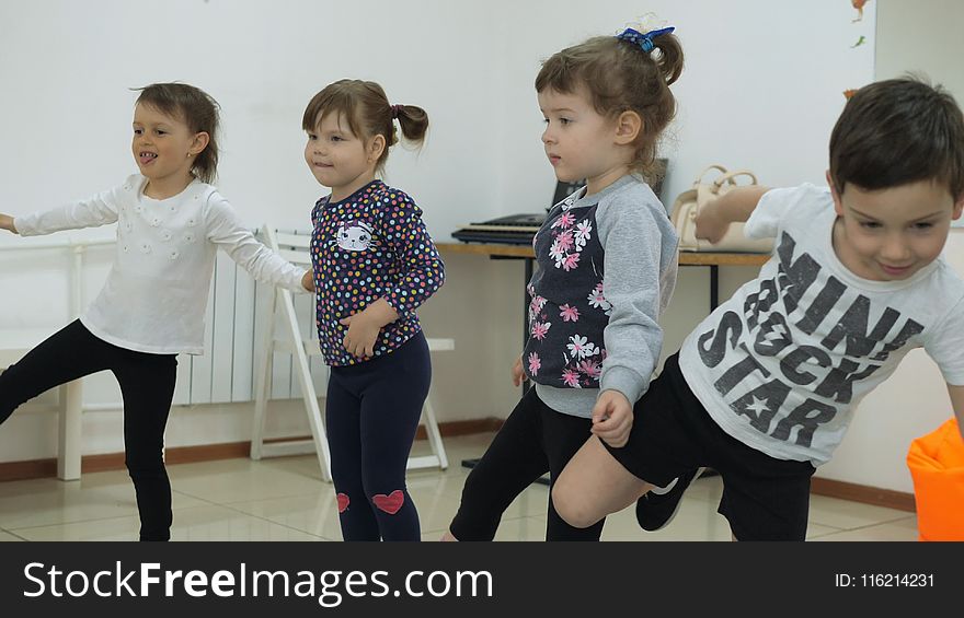 Children`s developing a game room. Emotions of young children during entertaining classes. The guys stand in line stepping from foot to foot. Children raise one leg high and keep balance.