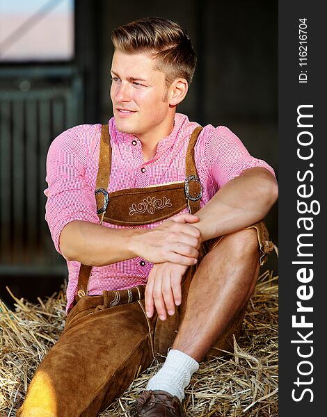 Blond bavarian man sitting on a haystack