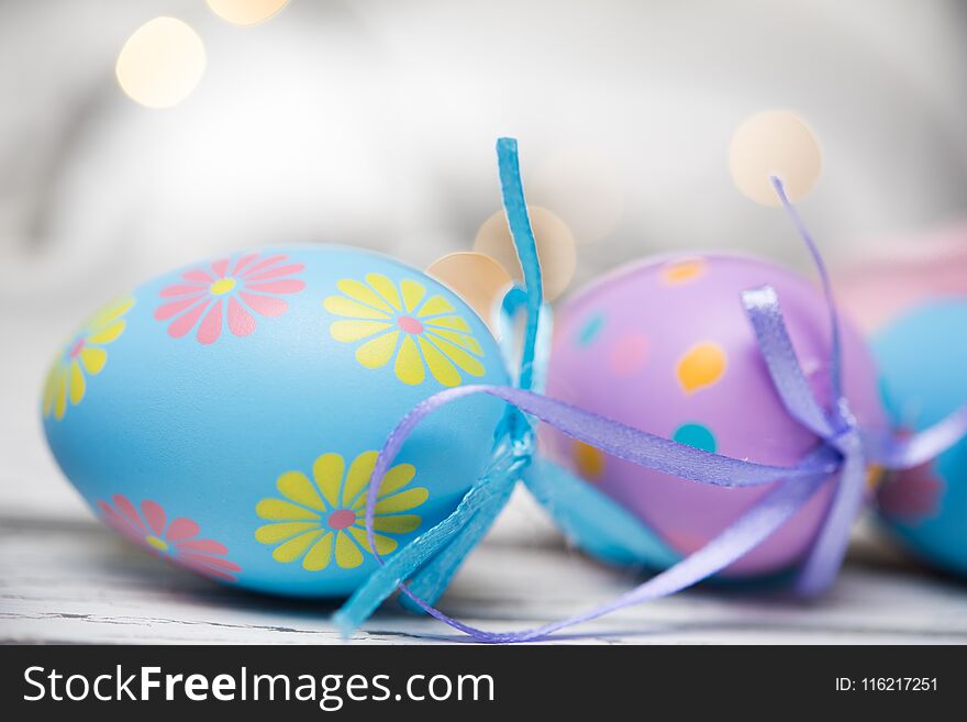 A group of pastel colored Easter eggs on a white, aged wooden background with copy space. A group of pastel colored Easter eggs on a white, aged wooden background with copy space.