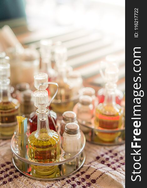 Old vintage glass bottles containing oil, vinegar, salt and pepper on a table in restaurant