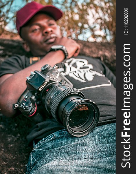 Selective Focus Black Nikon Dslr Camera With Zoom Lens on Lap Photo