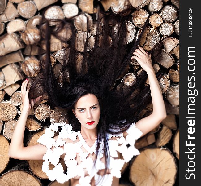 Woman Lying Down On Bunch Of Logs