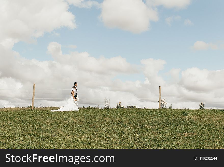 Couple in Wedding Suit and Dress on an Open Fiele