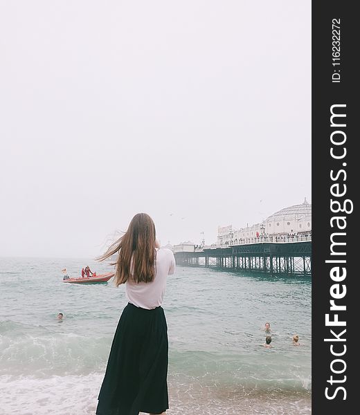 Woman Wearing White Shirt and Black Skirt Standing on Seashore