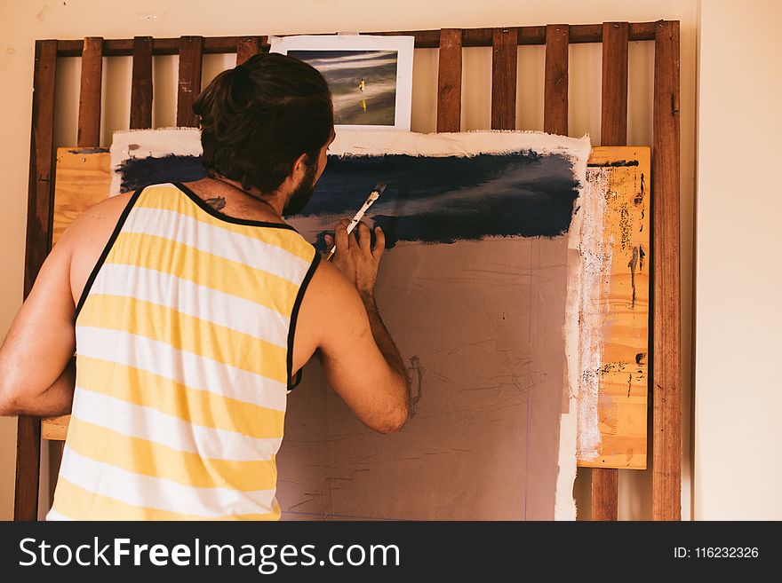 Man In White And Yellow Stripe Tank Top Painting On Canvas