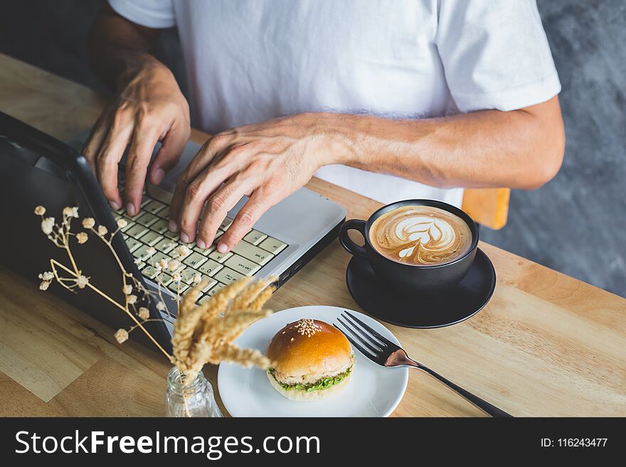 A hand of man pressing computer on table with coffee and bread in coffee shop. A hand of man pressing computer on table with coffee and bread in coffee shop