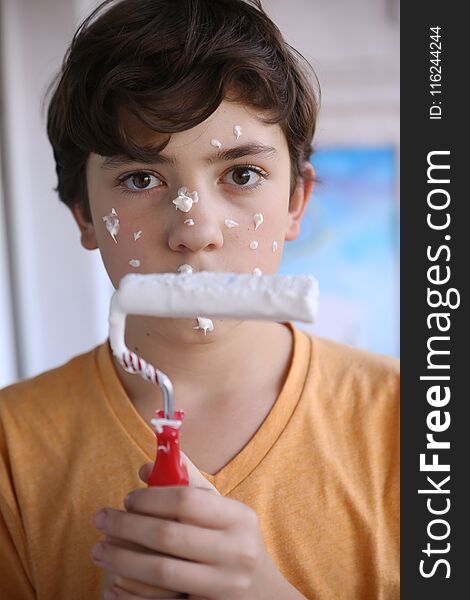 Smiling Teenager Boy With White Paint Roller And Dirty Face Make Repaint