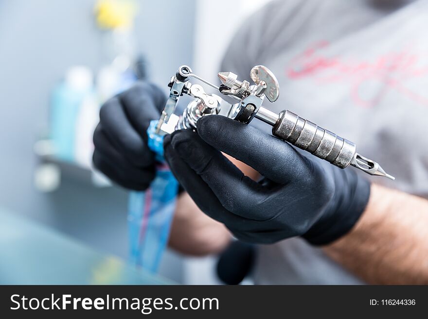 Close-up of the hands of a skilled tattoo artist wearing black gloves