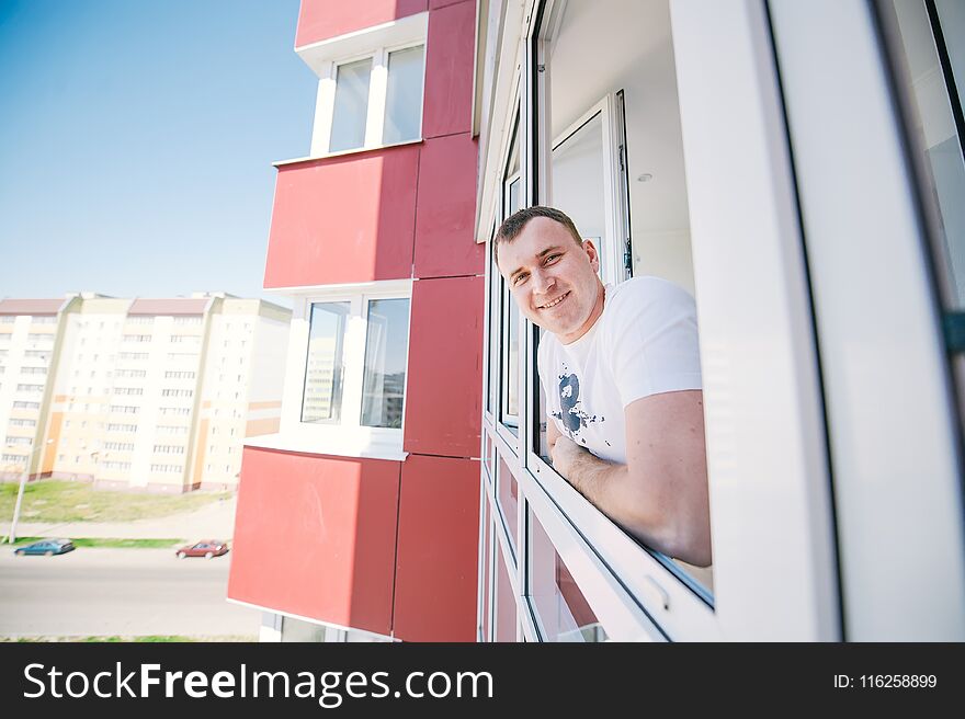 The cheerful guy standing on a balcony.