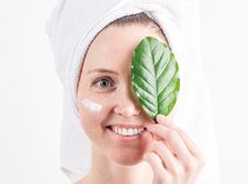 Natural Cosmetics: A Girl With A White Towel On Her Head Smiles And Covers One Eye With A Green Leaf. Royalty Free Stock Photography