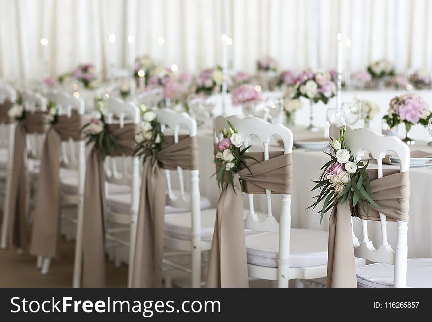 White chairs and tables decorated with flowers and fabric on the wedding day. White chairs and tables decorated with flowers and fabric on the wedding day