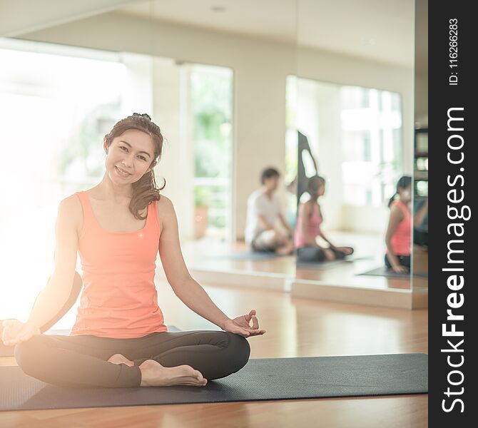 Attractive young Asian woman group exercising and sitting in yoga lotus position in yoga classes. asan. Attractive young Asian woman group exercising and sitting in yoga lotus position in yoga classes. asan