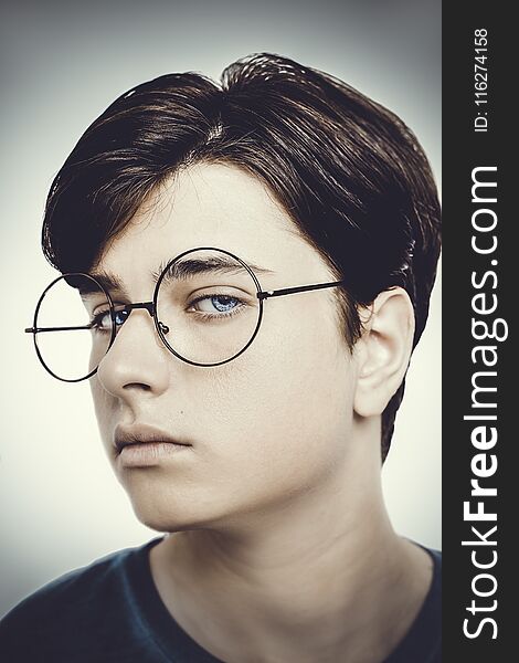 Portrait of a boy wearing eyeglasses blue eyes close, macro studio shot.