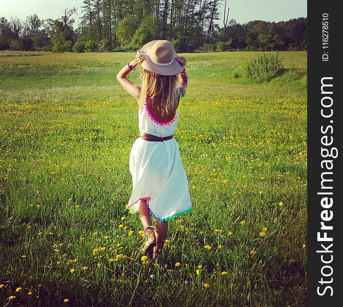 Boho girl with hat is walking on a green field. it is surrounded by beautiful spring colors, flowers and trees. Boho girl with hat is walking on a green field. it is surrounded by beautiful spring colors, flowers and trees.